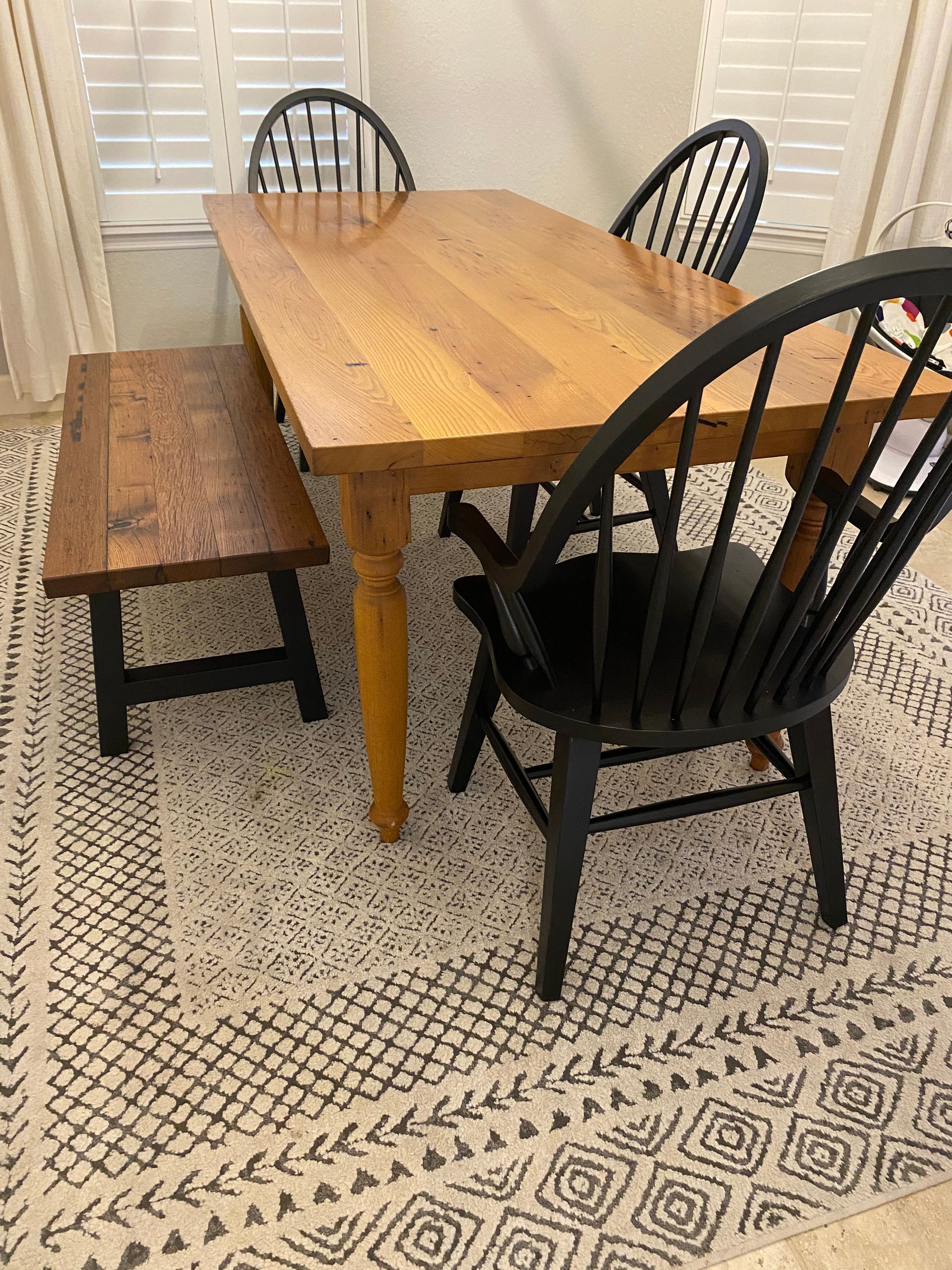 A wooden dining table with black chairs and a bench in a dining room.