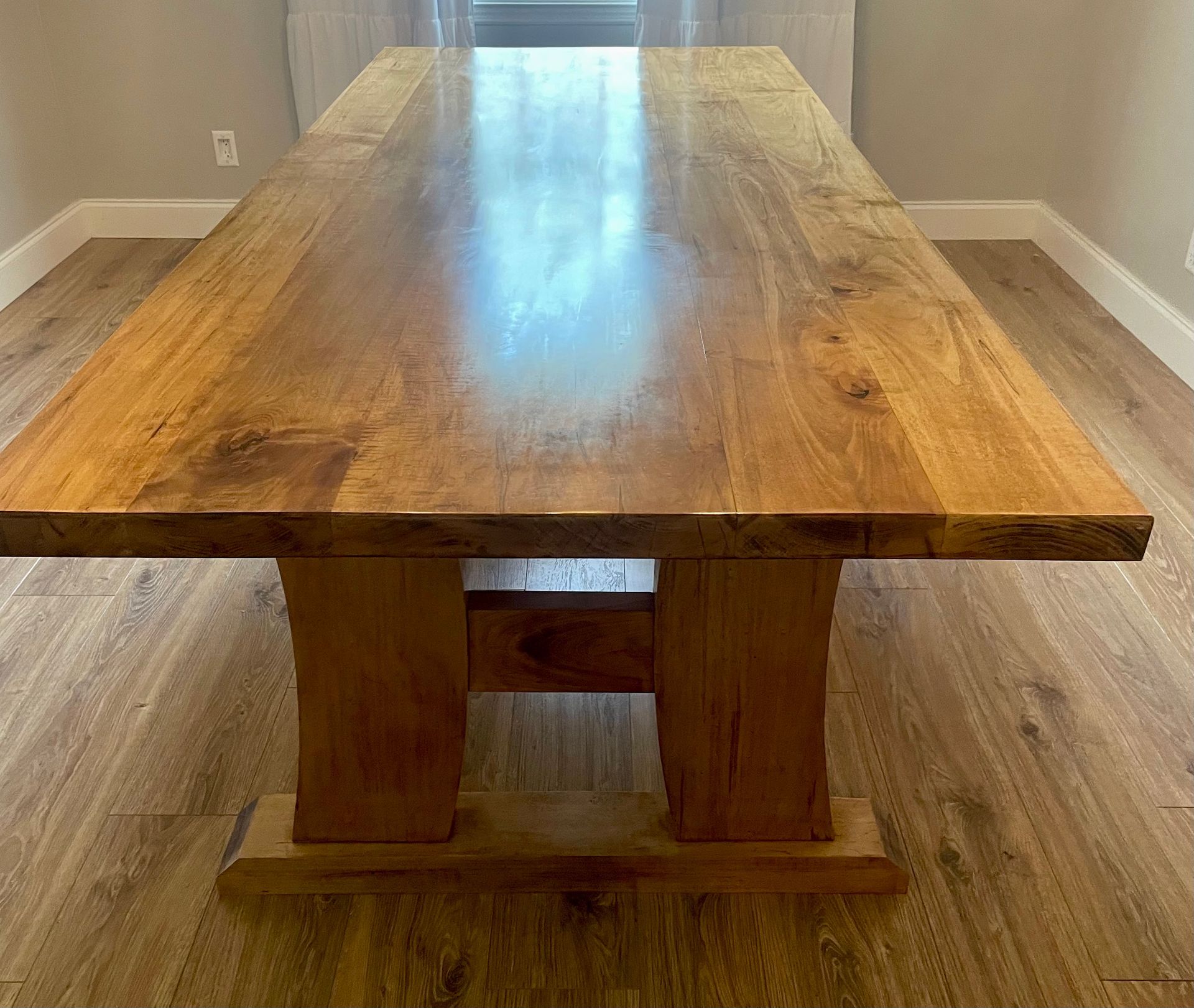 A long wooden table is sitting on a wooden floor in a room.