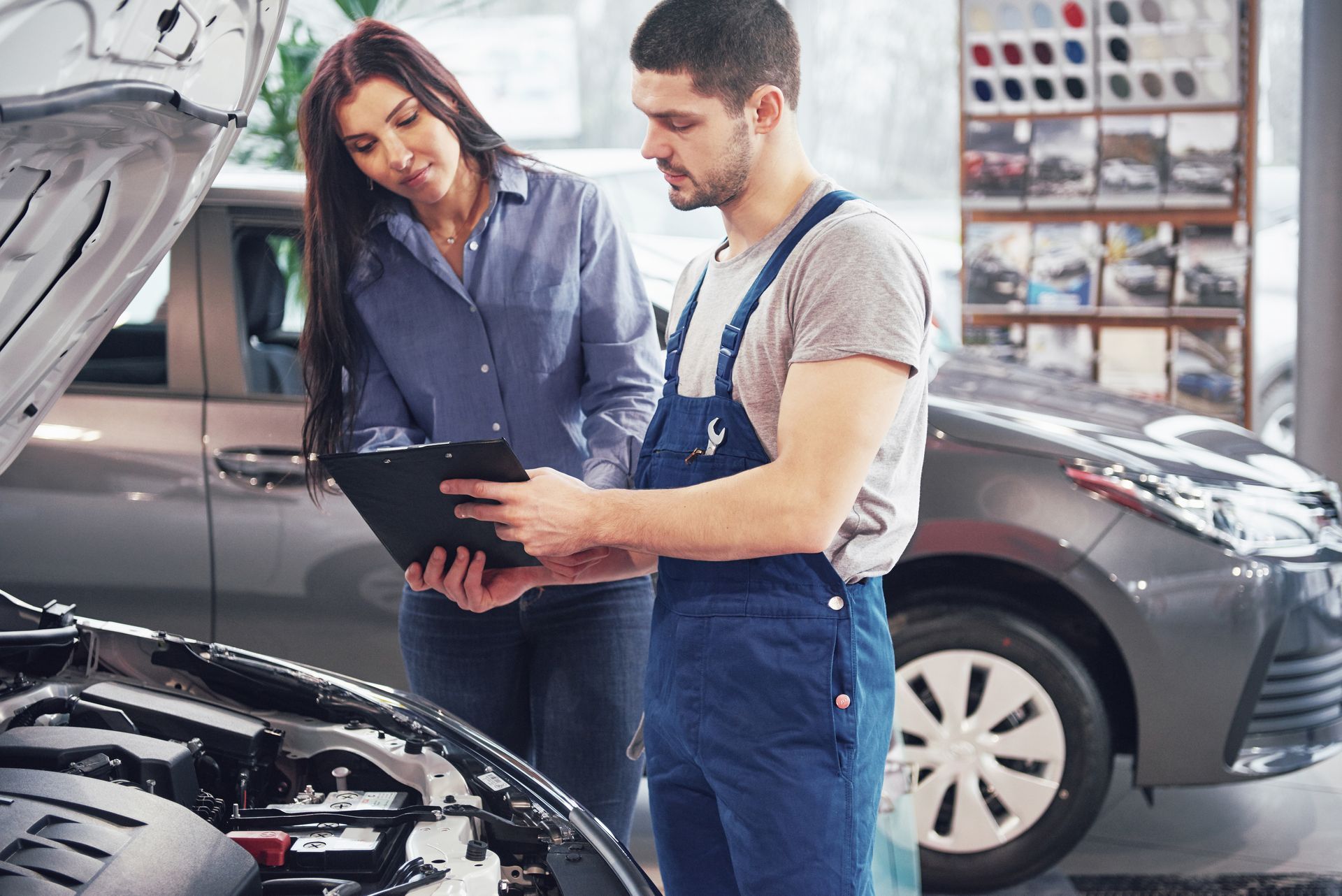 A man and a woman are looking under the hood of a car.