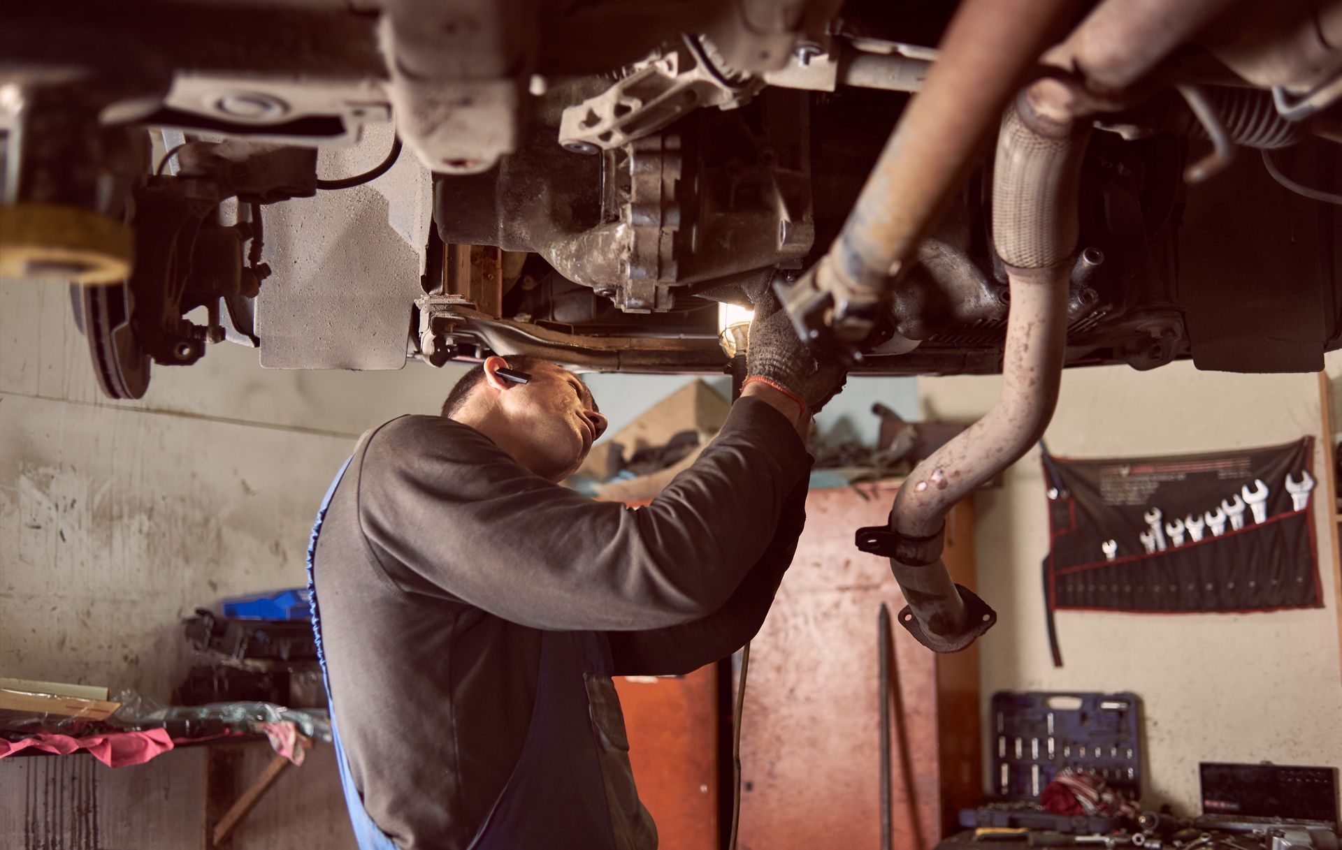 A man is working under a car in a garage.