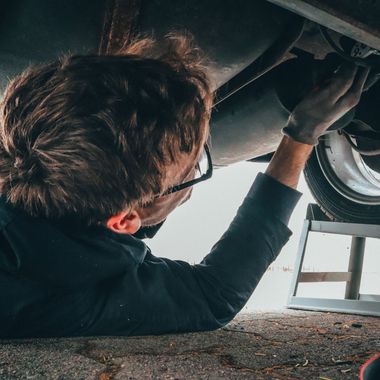 A man is laying on the ground working under a car.