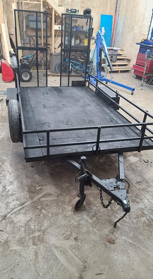 A black trailer is sitting on top of a concrete floor in a garage.