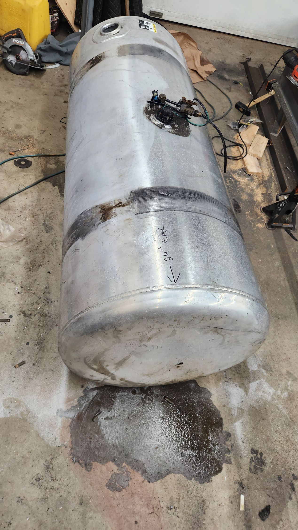 A large aluminum tank is sitting on the ground in a garage.