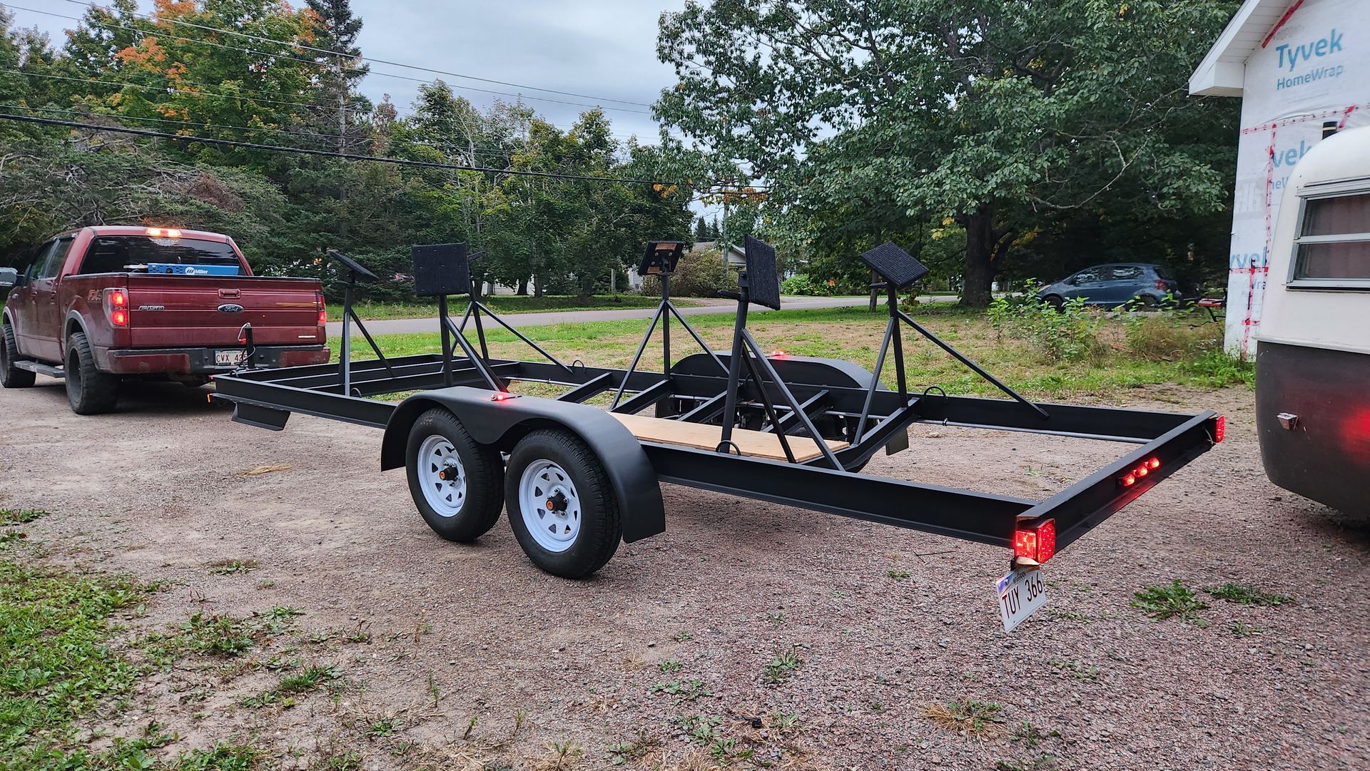 A red truck is towing a trailer with kayaks on it.