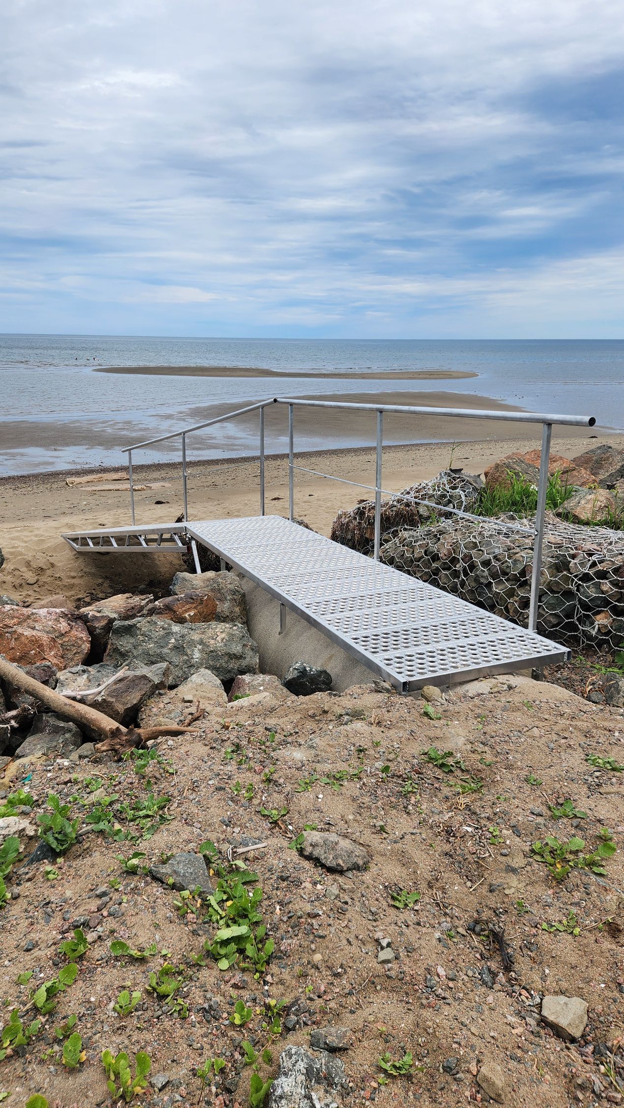 A metal dock is sitting on the beach next to the ocean.