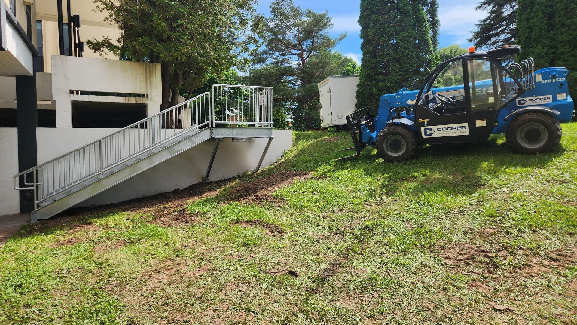 A blue tractor is parked in a grassy field in front of a building.