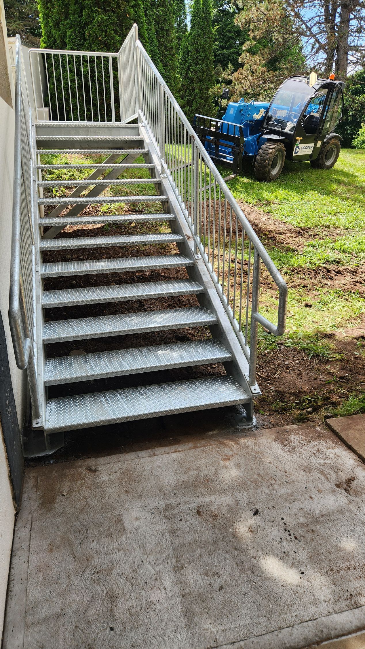 A metal staircase with a tractor in the background.