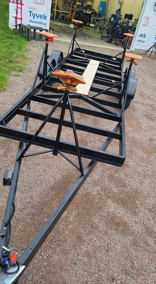 A trailer is sitting on top of a gravel road.