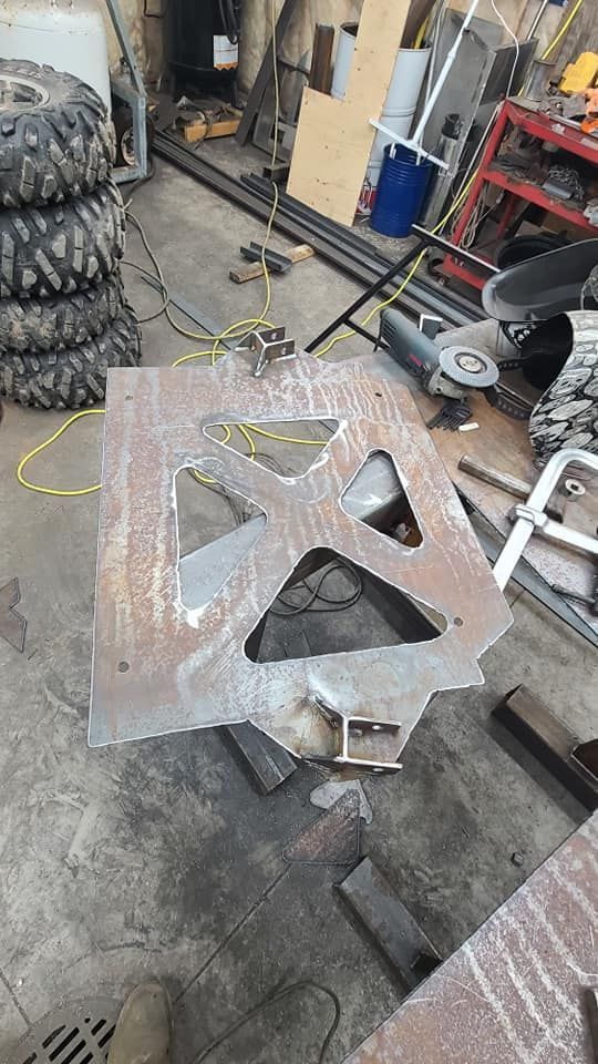 A piece of metal is sitting on the ground in a garage next to a stack of tires.