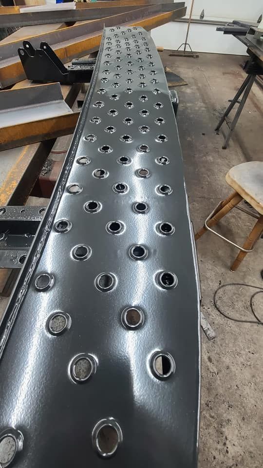 A metal ramp with holes in it is sitting on a table in a garage.