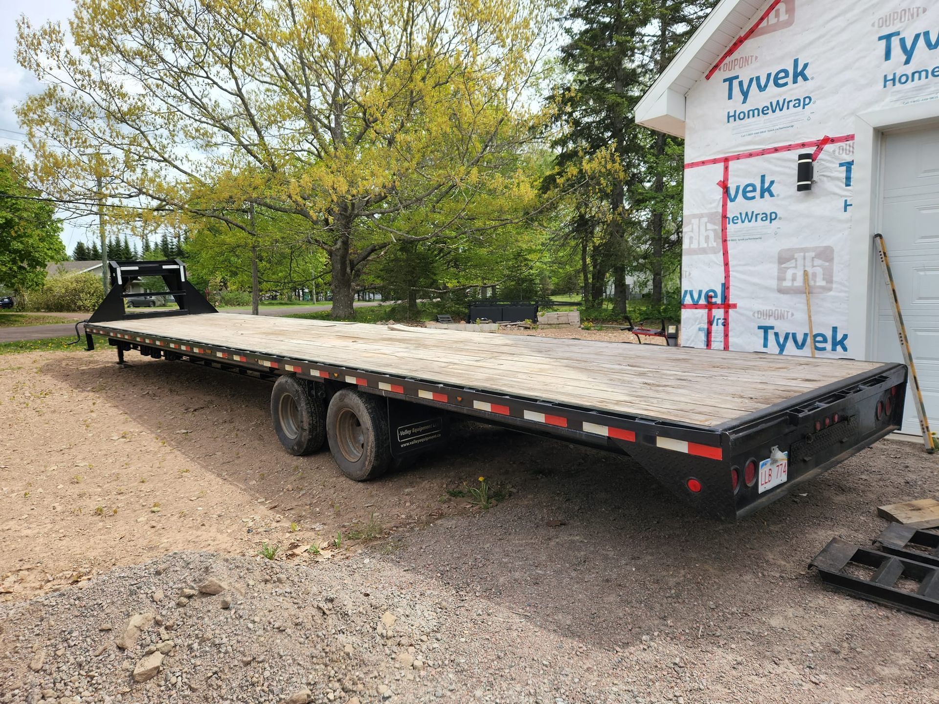 A large flatbed trailer is parked in front of a building under construction.