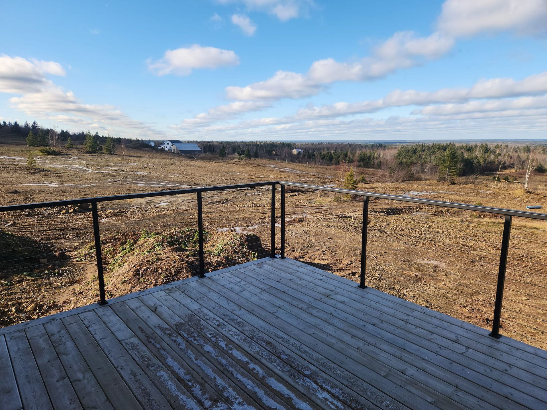 A wooden deck with a railing overlooking a field