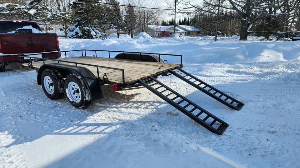 A trailer is parked in the snow next to a truck.