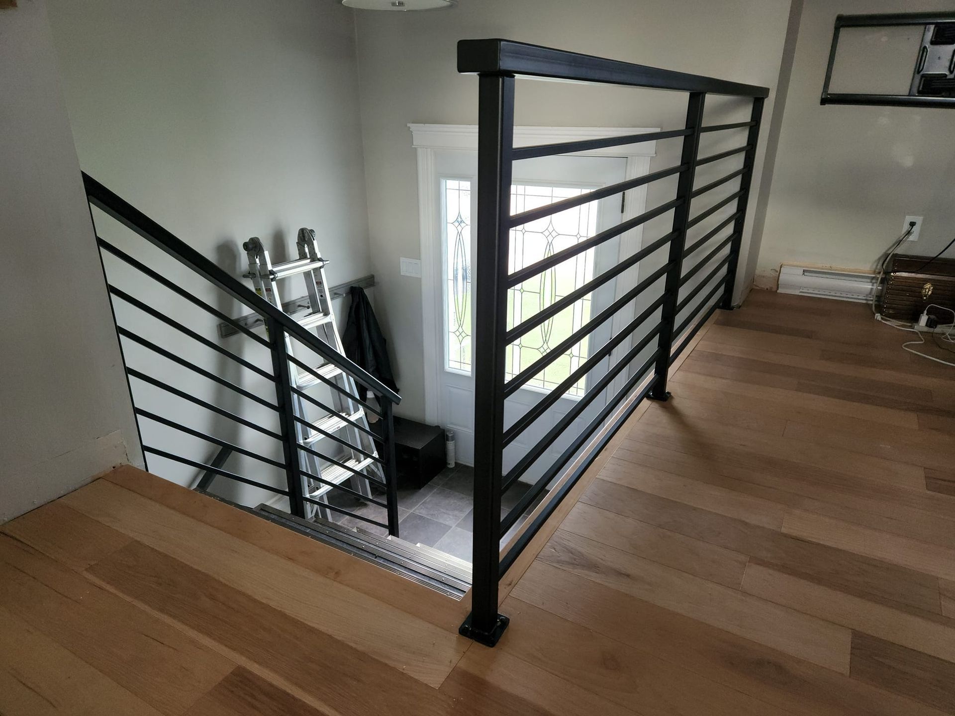 A staircase with a black railing and wooden floors