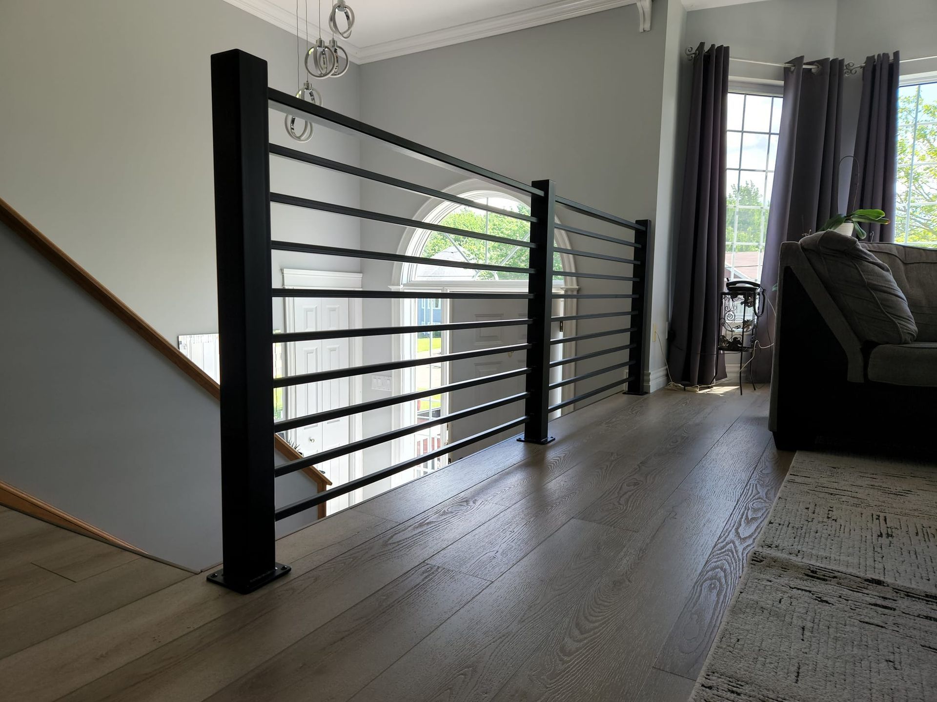 A living room with a staircase and a black railing.