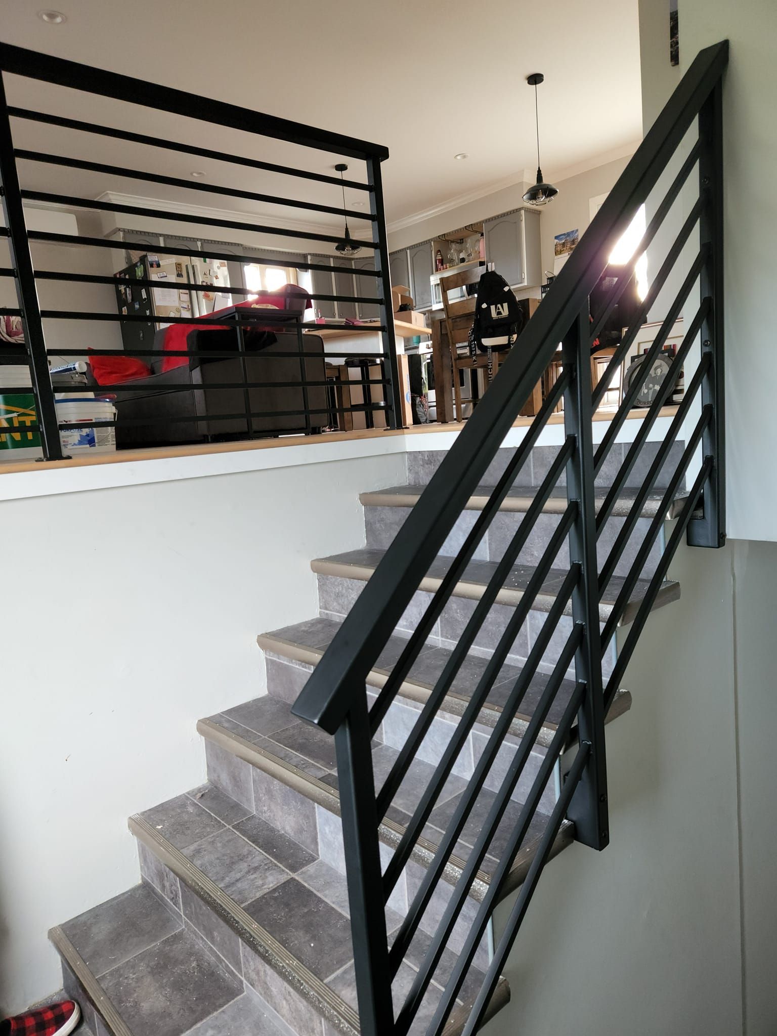 A staircase with a black railing leading up to a living room