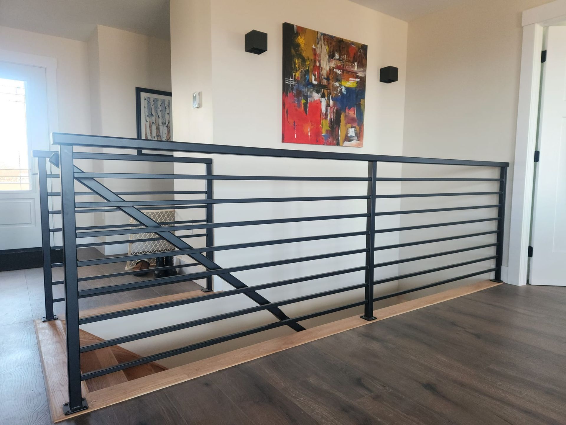 A staircase with a black railing and a painting on the wall
