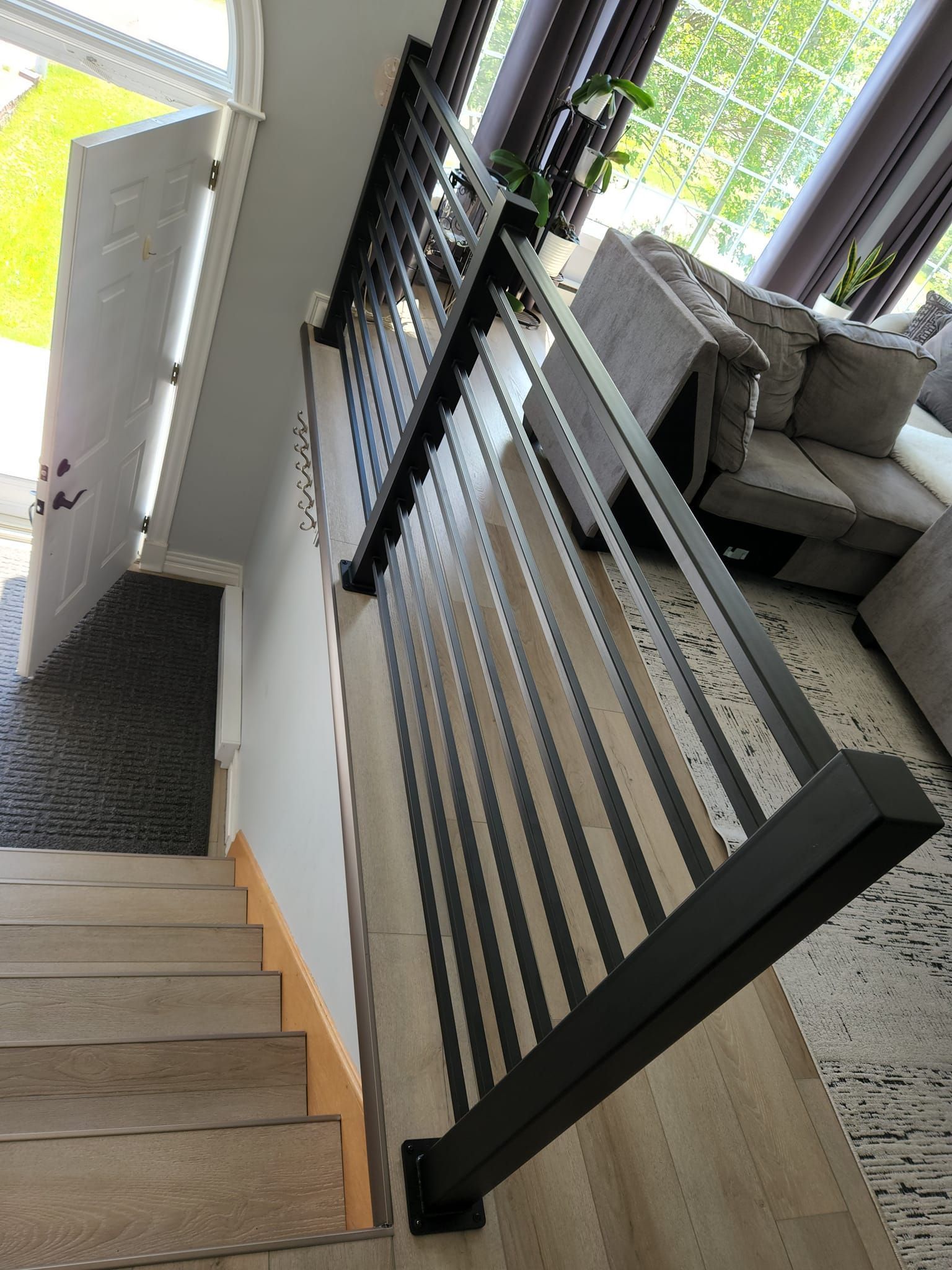 A staircase with a black railing leading up to a living room.