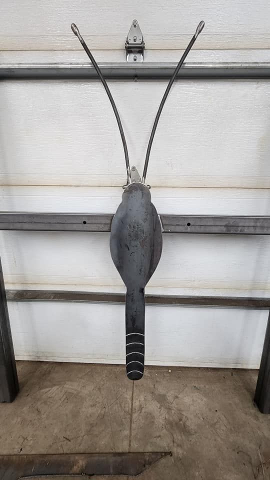 A metal sculpture of a moth is hanging on a garage door.