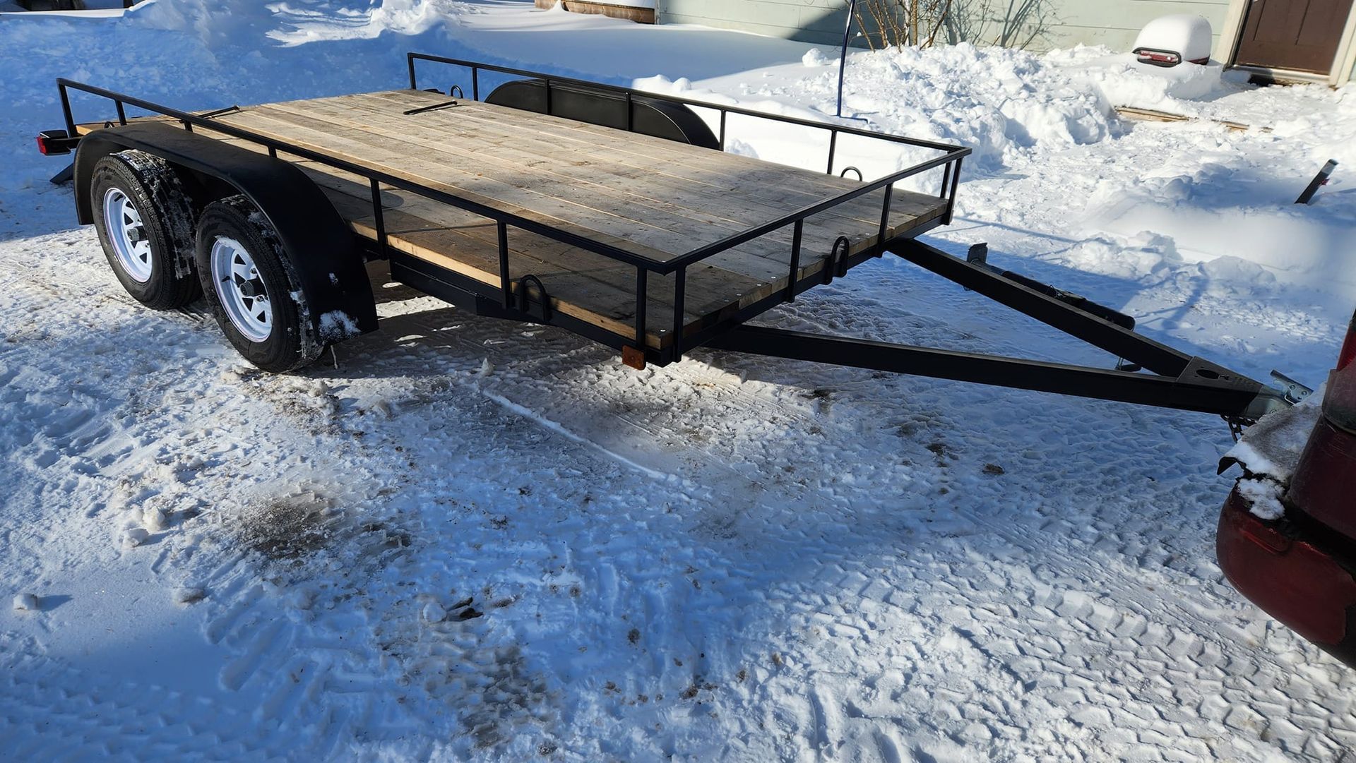 A trailer is parked in the snow next to a truck.
