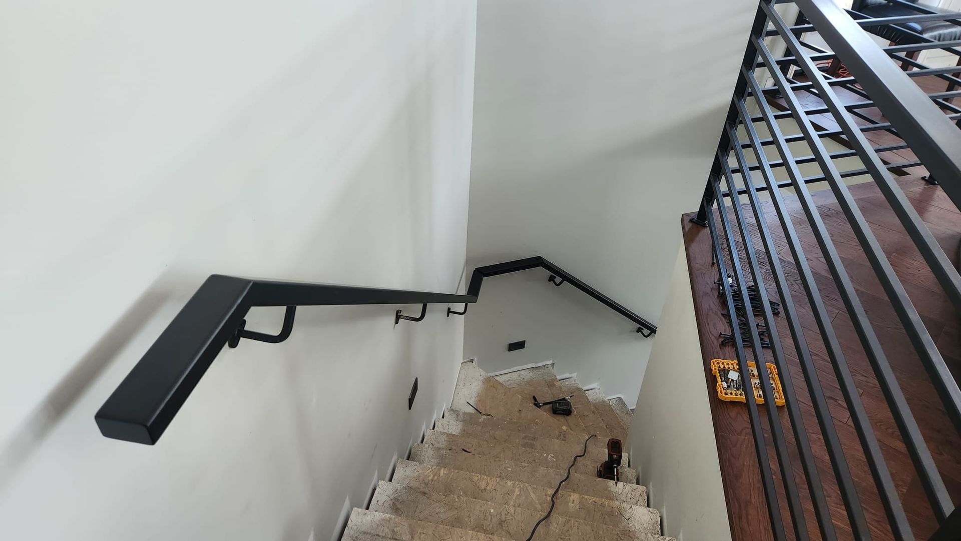 A staircase with a black railing and a white wall.
