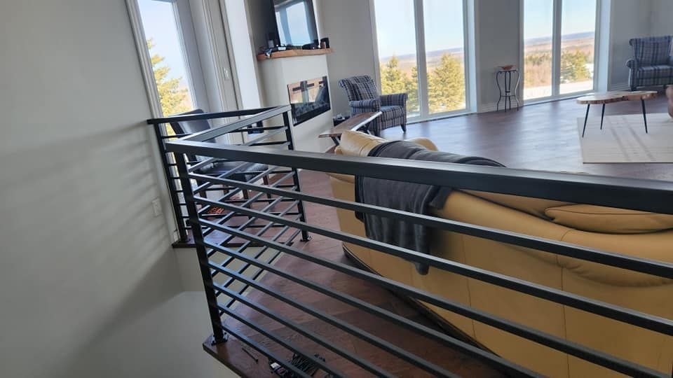 A living room with a yellow couch and a black railing.