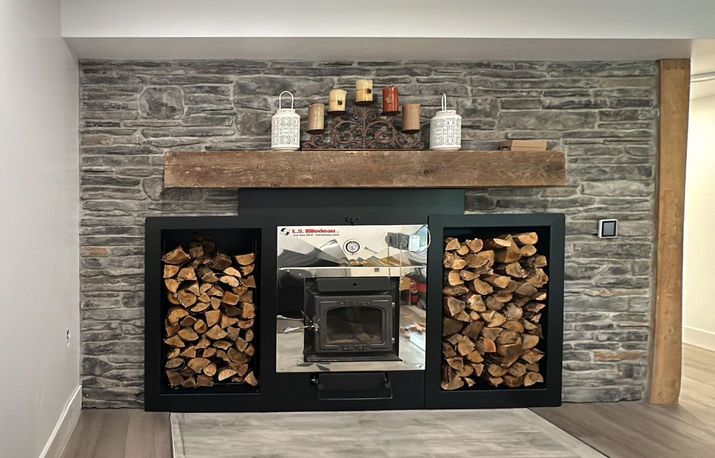 A living room with a fireplace and a mantle filled with logs.