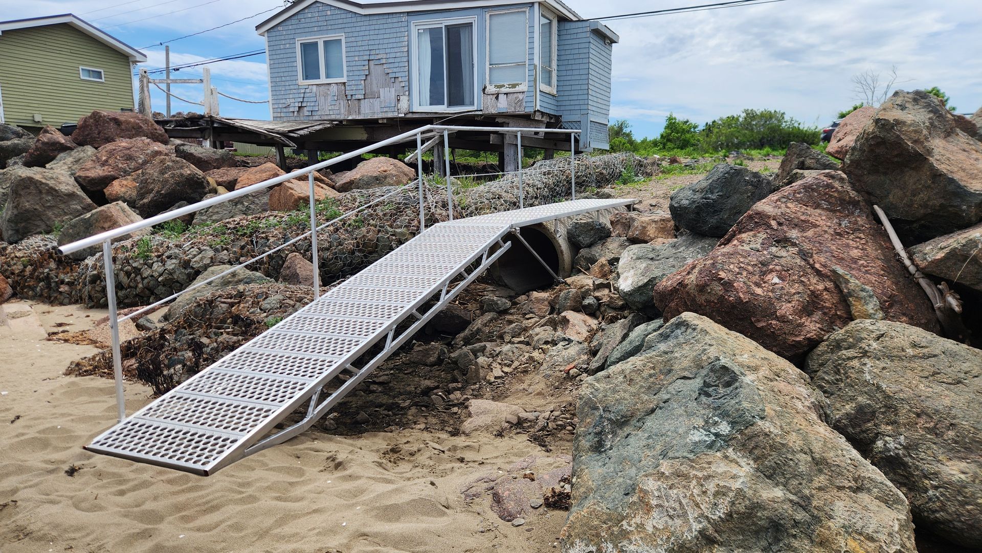 There is a ramp leading to a house on the beach.