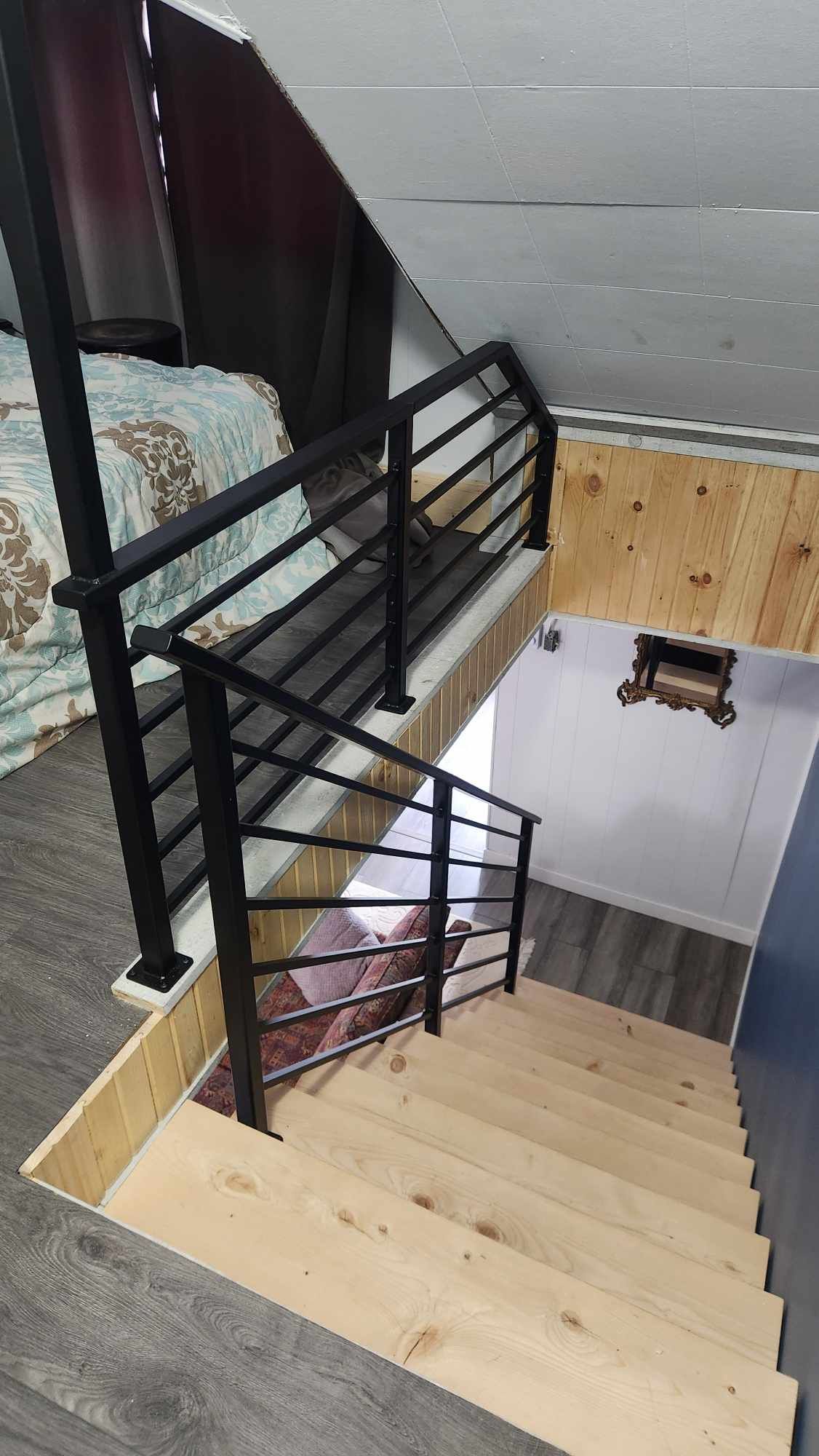 A wooden staircase with a metal railing leading up to the second floor of a house.