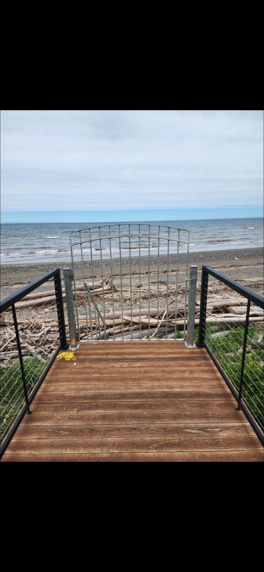 A wooden dock leading to the beach with a view of the ocean.