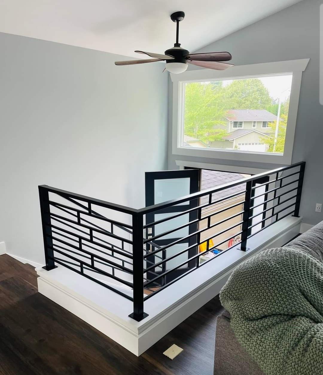 A living room with a balcony and a ceiling fan