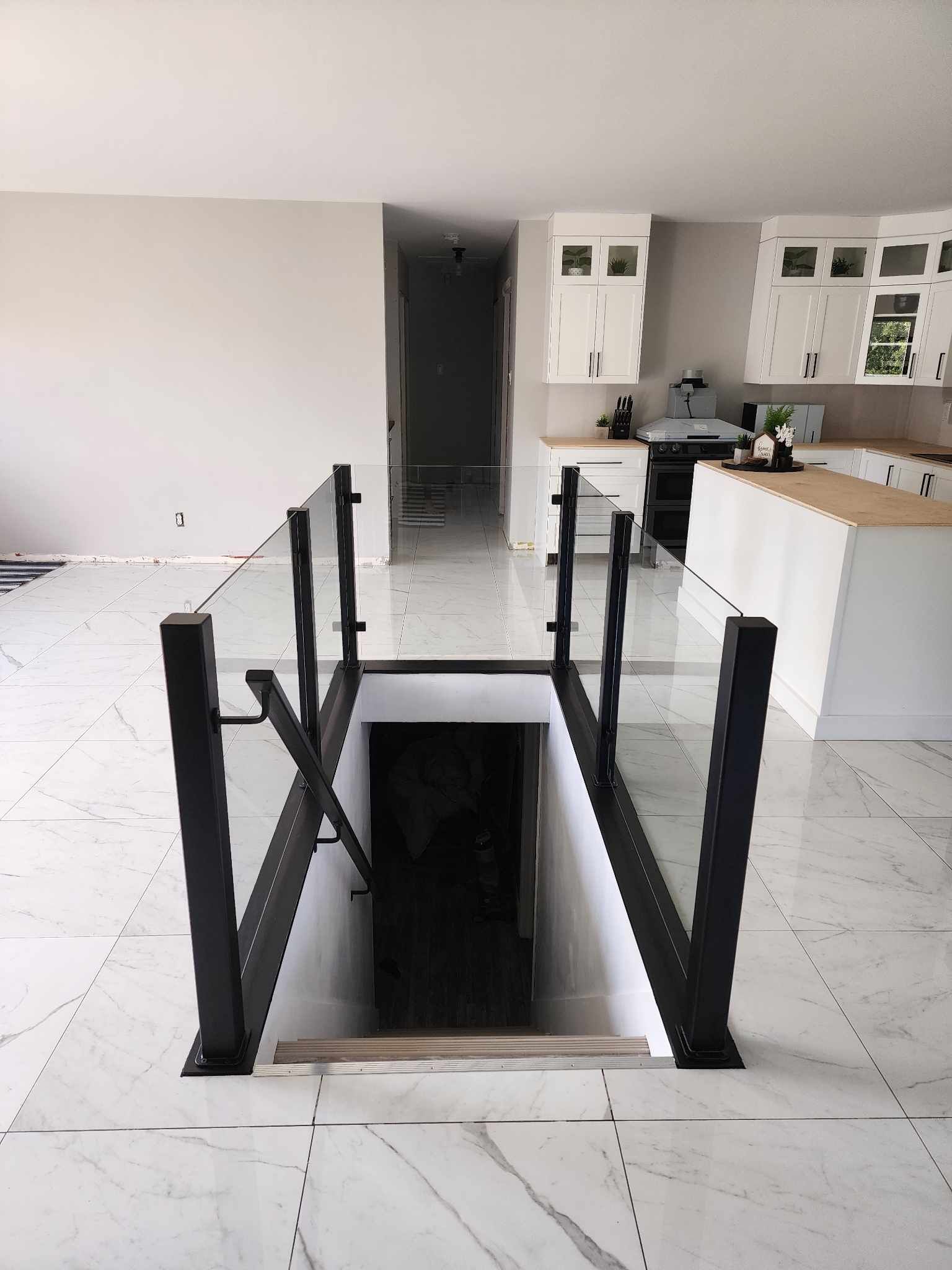 A staircase leading to a basement in a house with a glass railing.