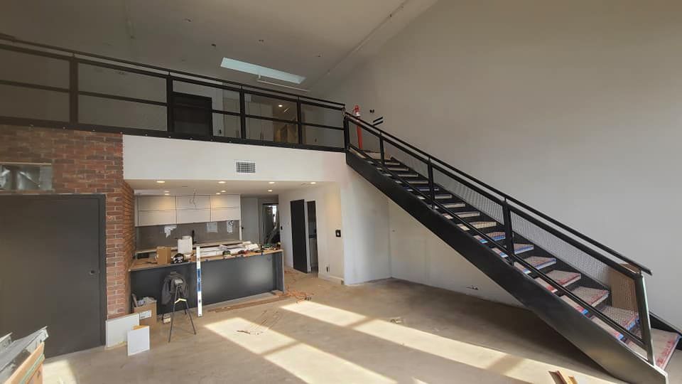 A large room with a staircase leading up to the second floor.