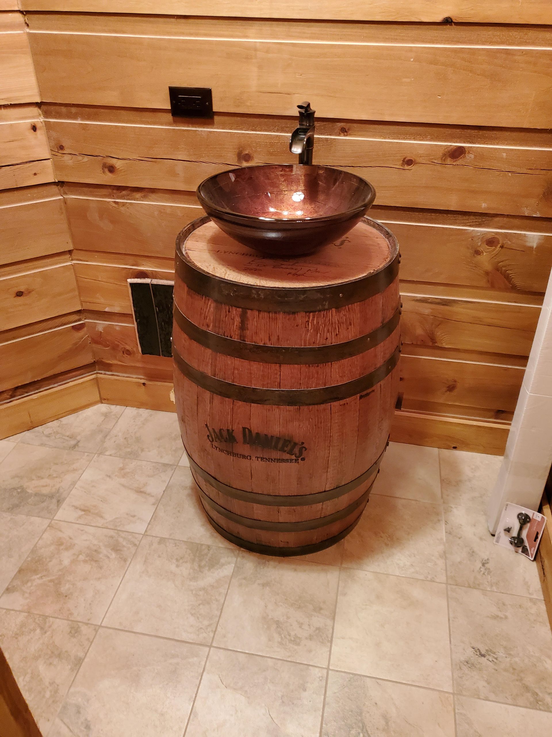 A bathroom sink is sitting on top of a wooden barrel.