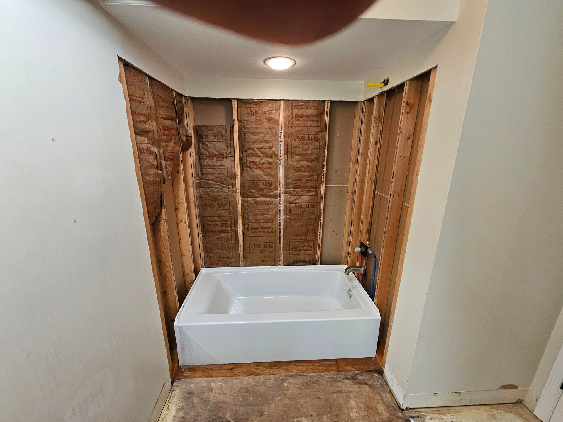 A bathtub is sitting in a bathroom under construction.