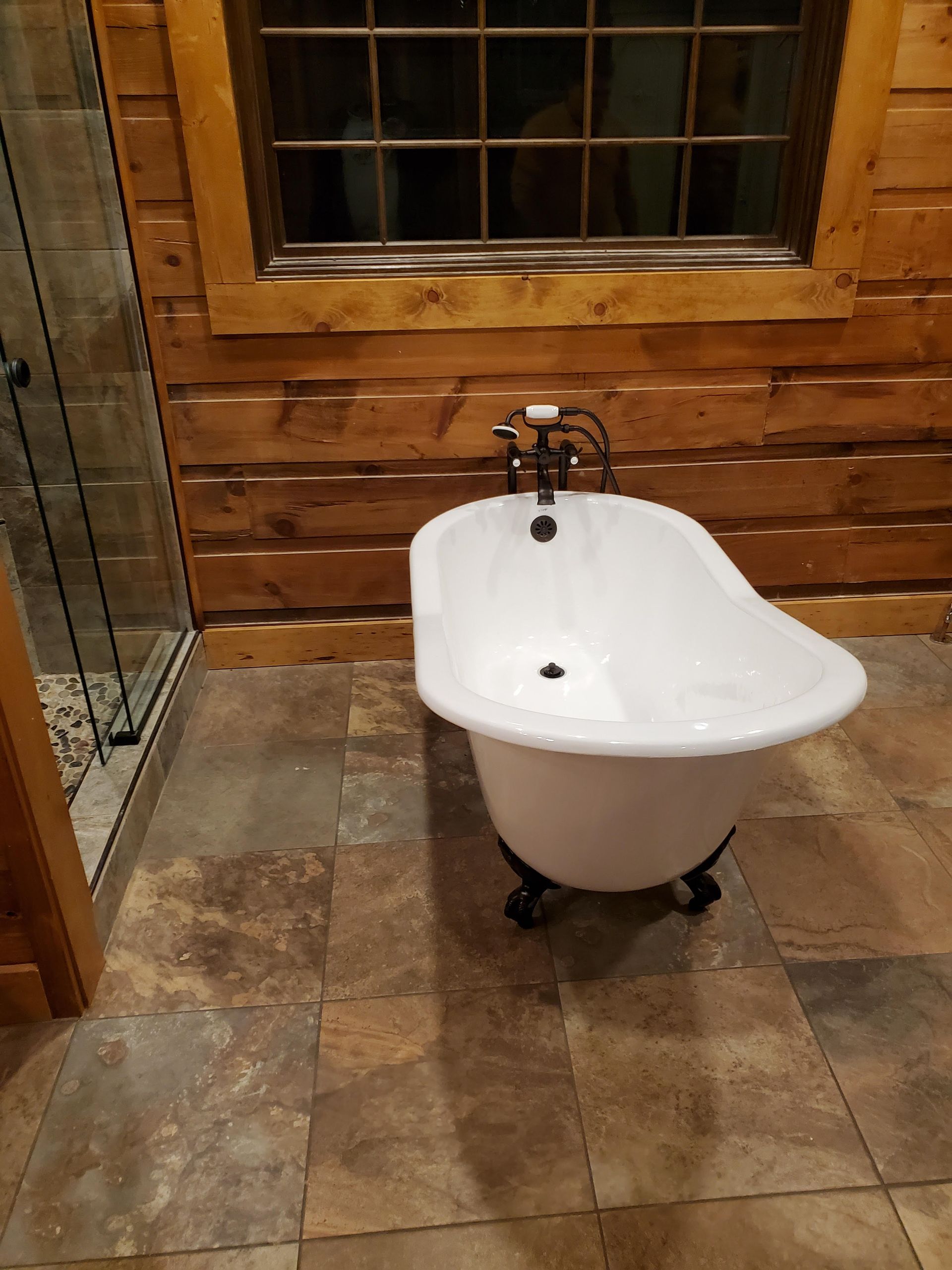 A bathtub is sitting on a tiled floor in a bathroom next to a window.