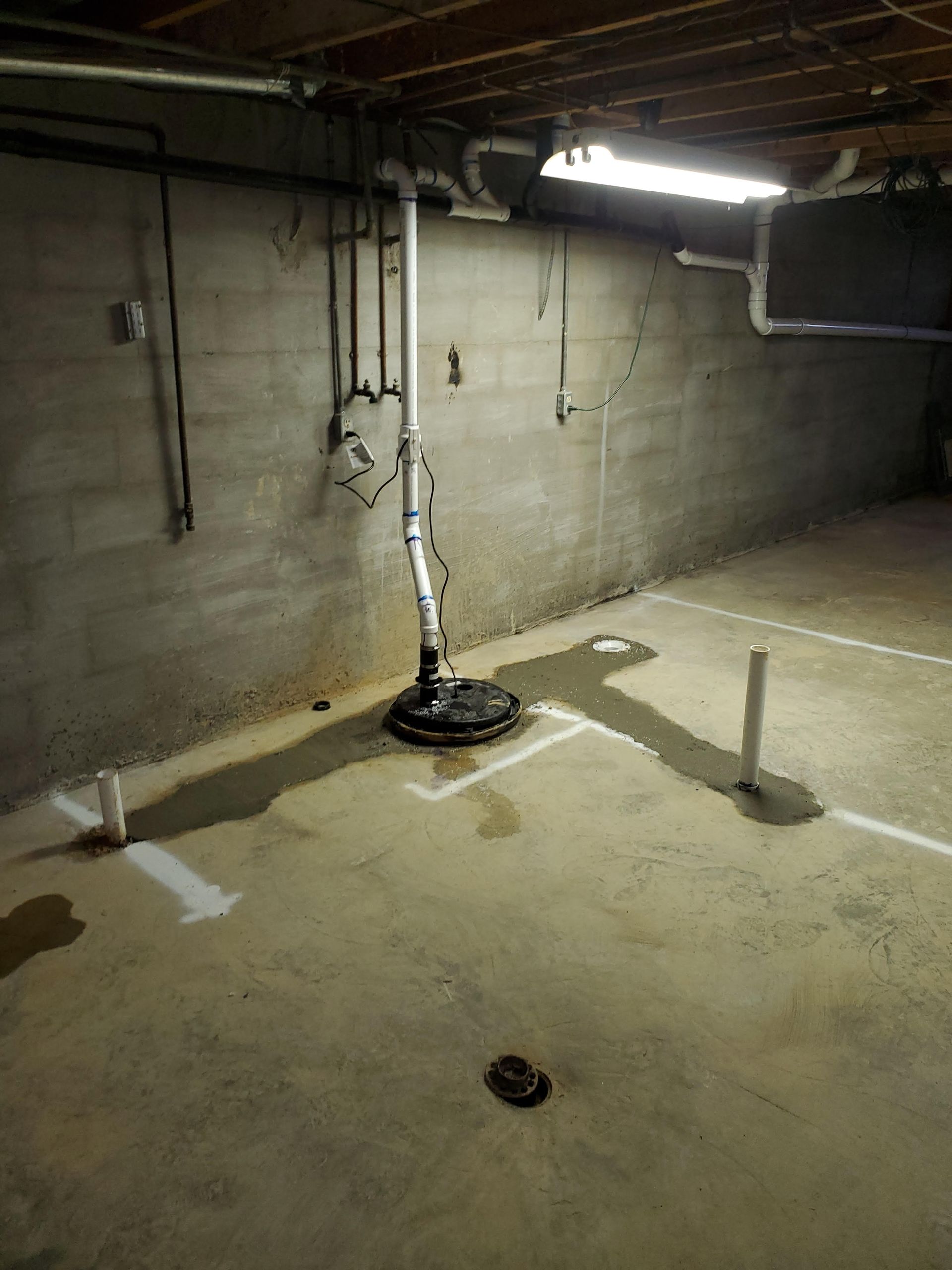 A basement with a drain and pipes in it