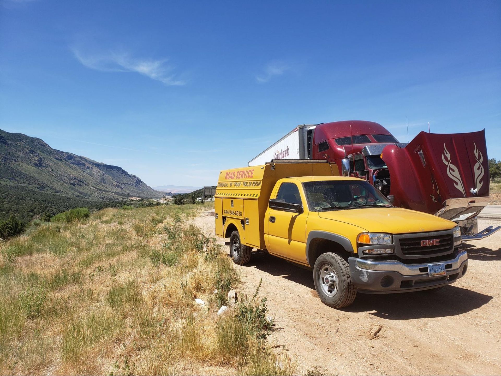 A yellow truck is parked on the side of a dirt road.