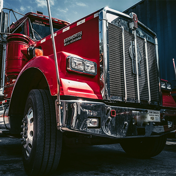 A red semi truck is parked in front of a building.