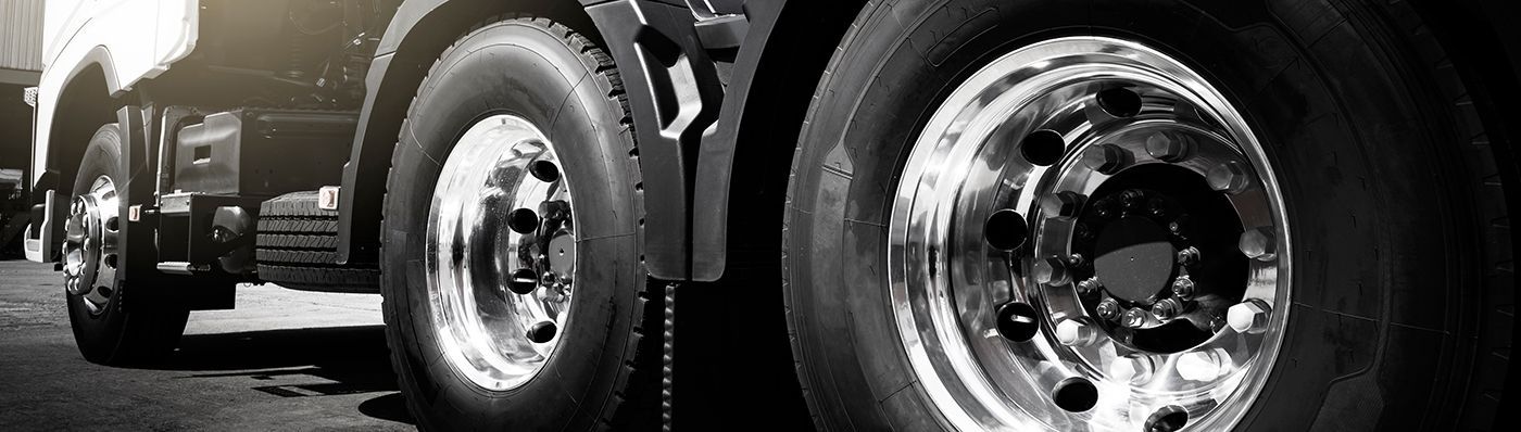 Red Kenworth semi-truck, chrome grill and details, parked outdoors.