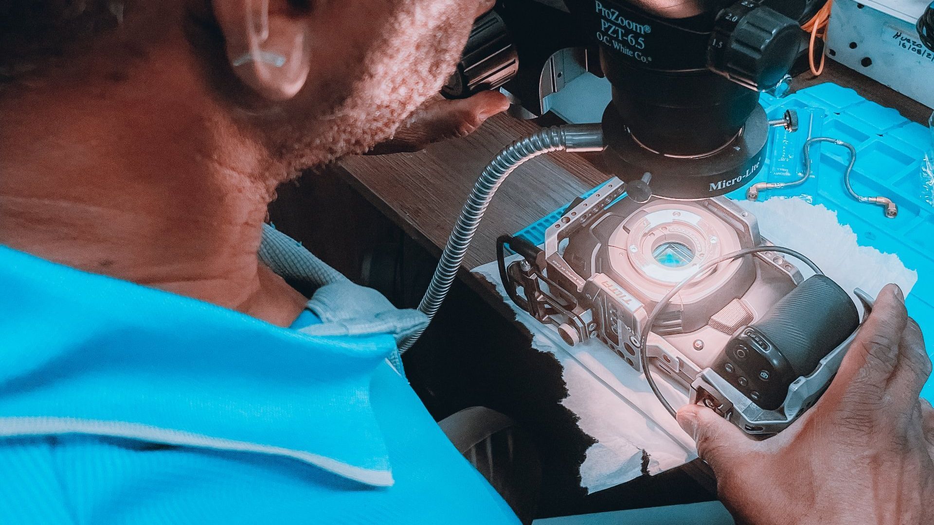 A person is using a brush to clean the lens of a camera.