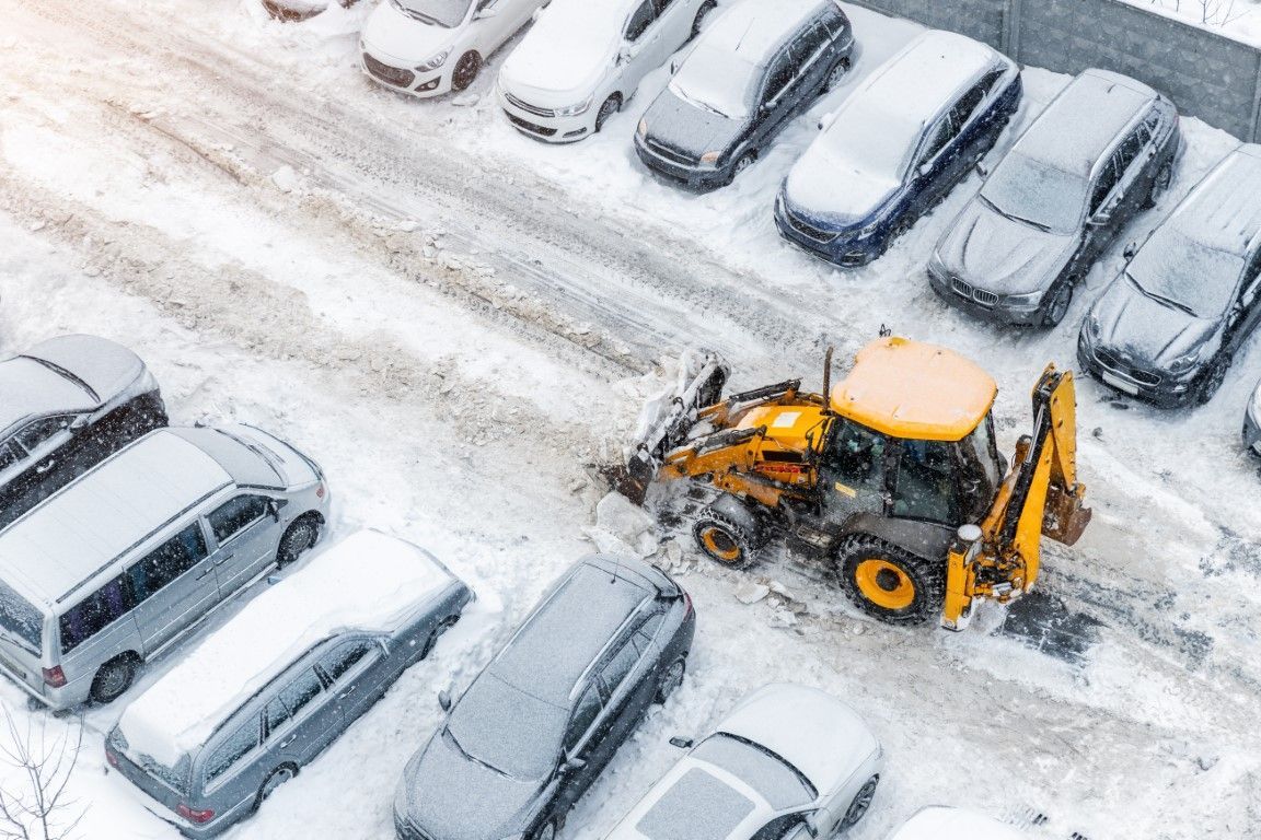 Yellow wheel loader clearing snow in parking lot.