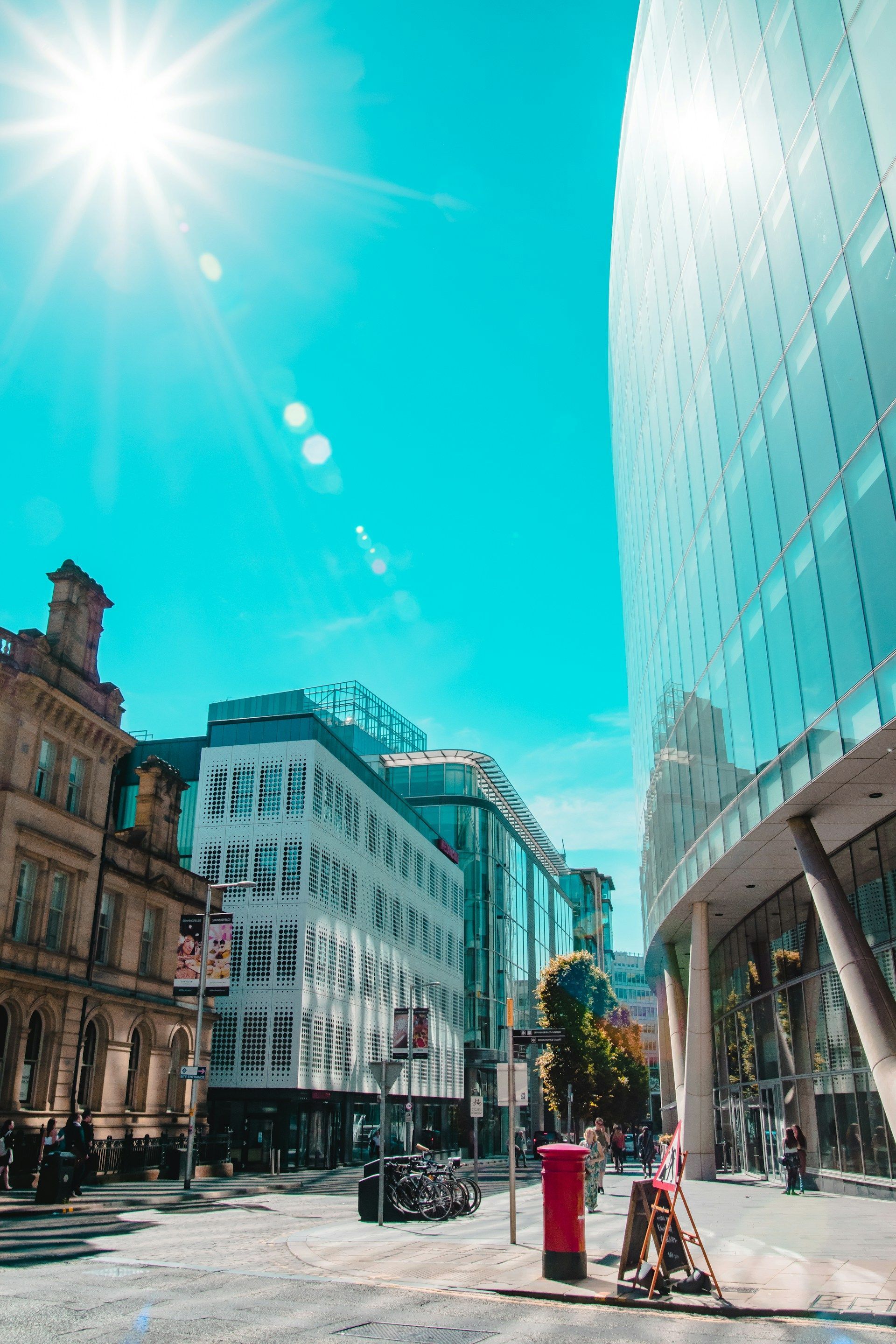 En bygate med en stor bygning i bakgrunnen og solen som skinner gjennom vinduene.
