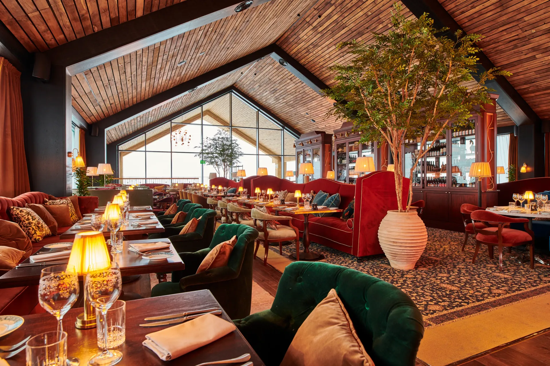 En restaurant med bord og stoler og et tre midt i rommet.