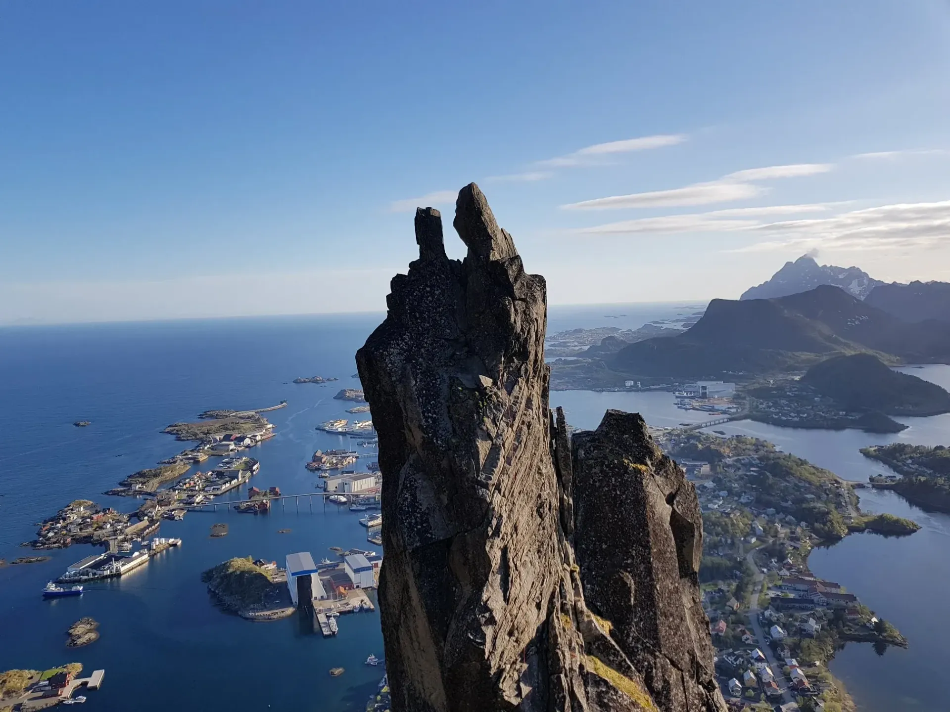 En person står på toppen av et fjell med utsikt over havet.