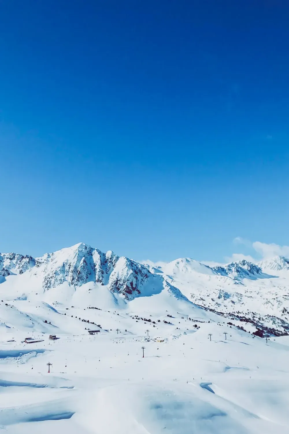 En snødekt fjellkjede med en blå himmel i bakgrunnen