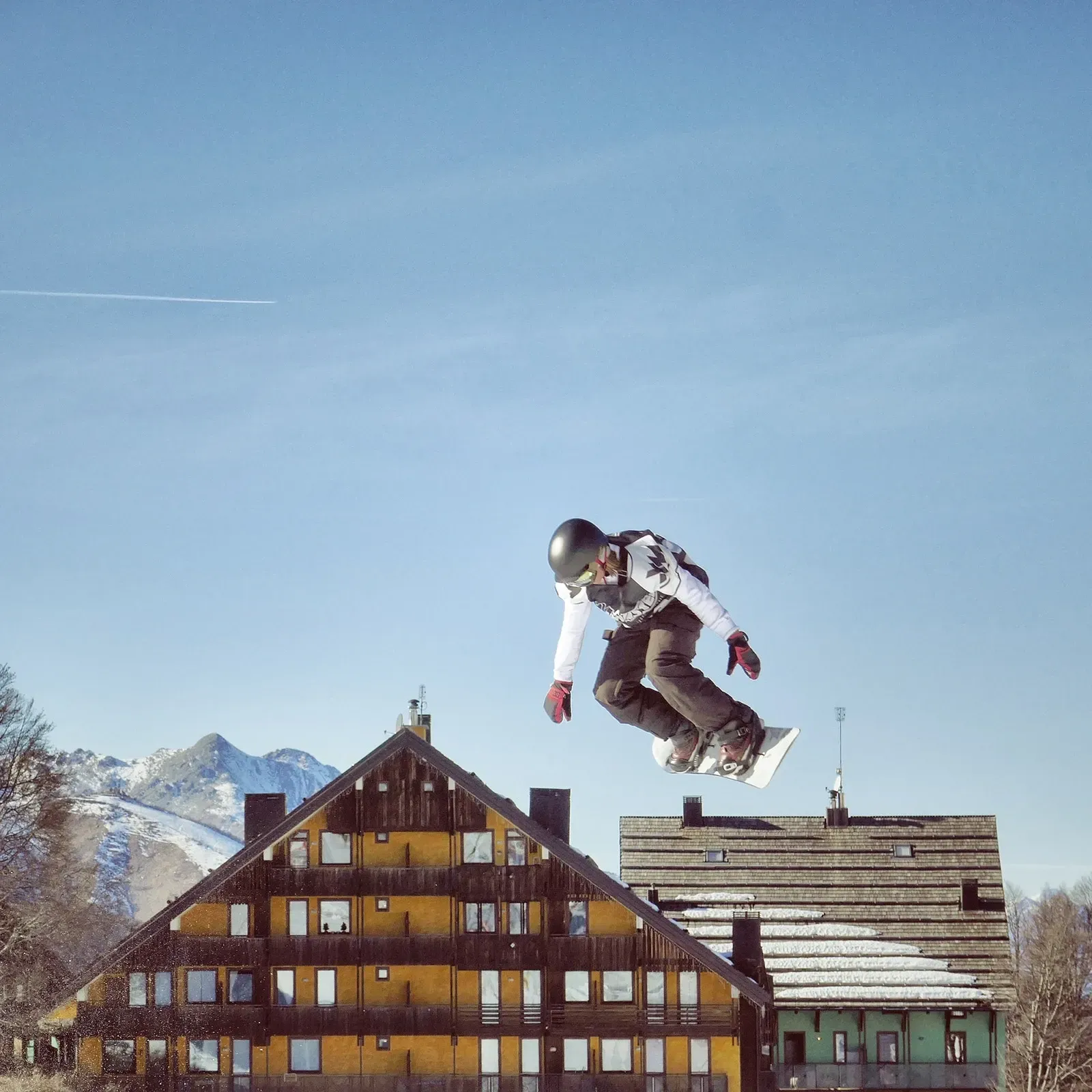 En snowboarder hopper i luften foran en bygning
