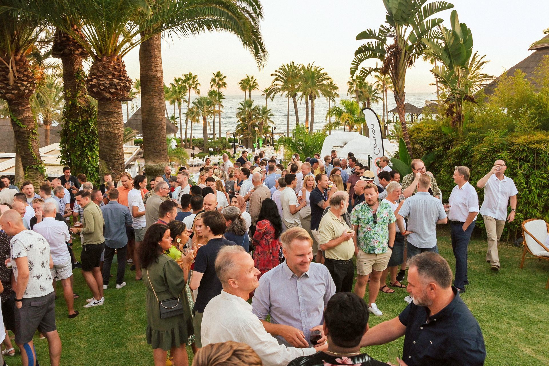 En stor gruppe mennesker står på toppen av en frodig grønn mark.