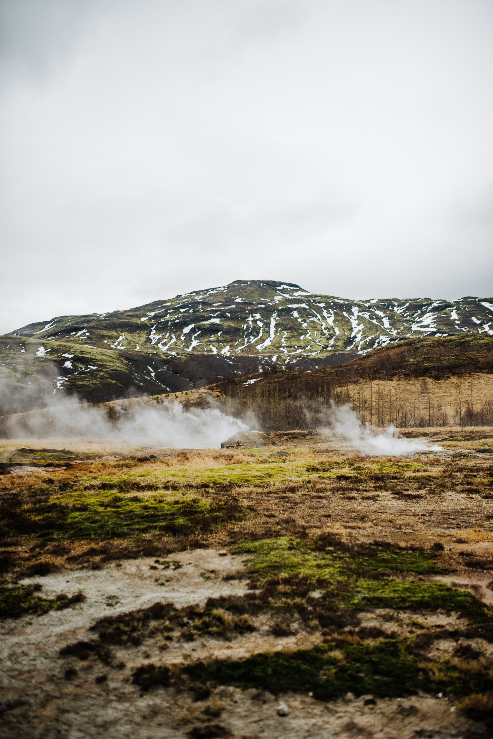 Et felt med røyk ut av det og et fjell i bakgrunnen.