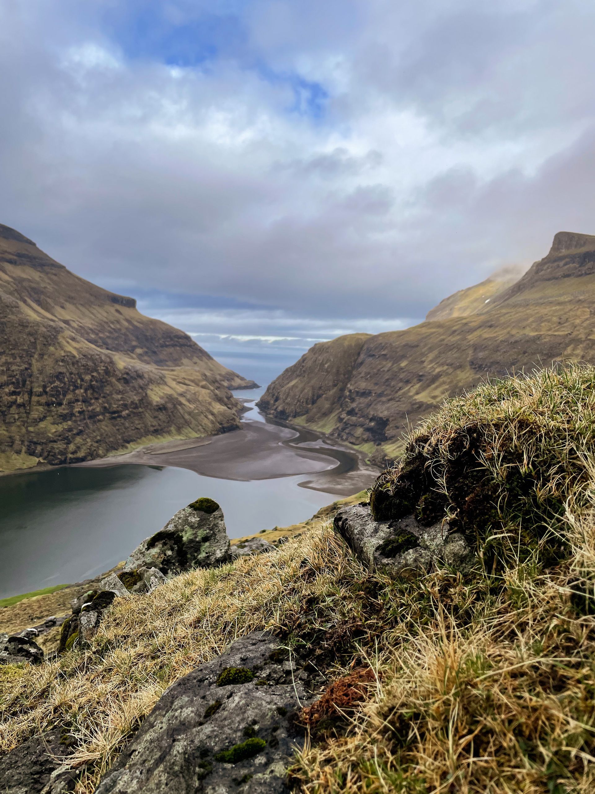 Utsikt over en innsjø omgitt av fjell på en overskyet dag.
